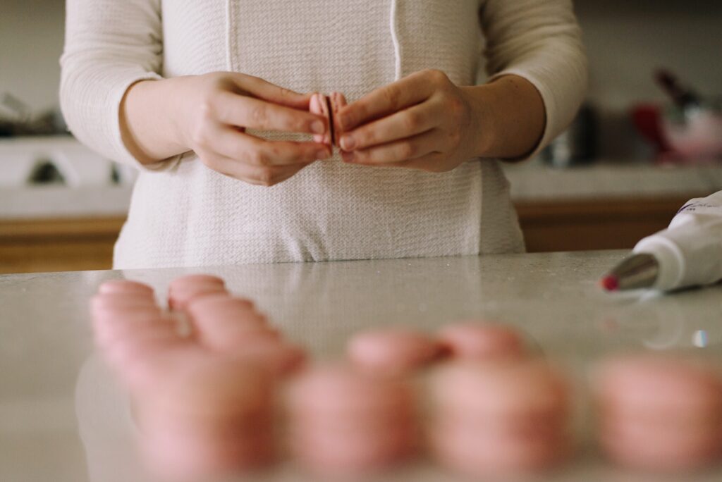 A person putting together two halves of a macaron