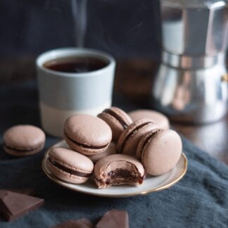 Chocolate macarons stacked on a white plate