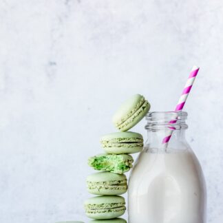 Pistachio macarons stacked against a bottle of milk