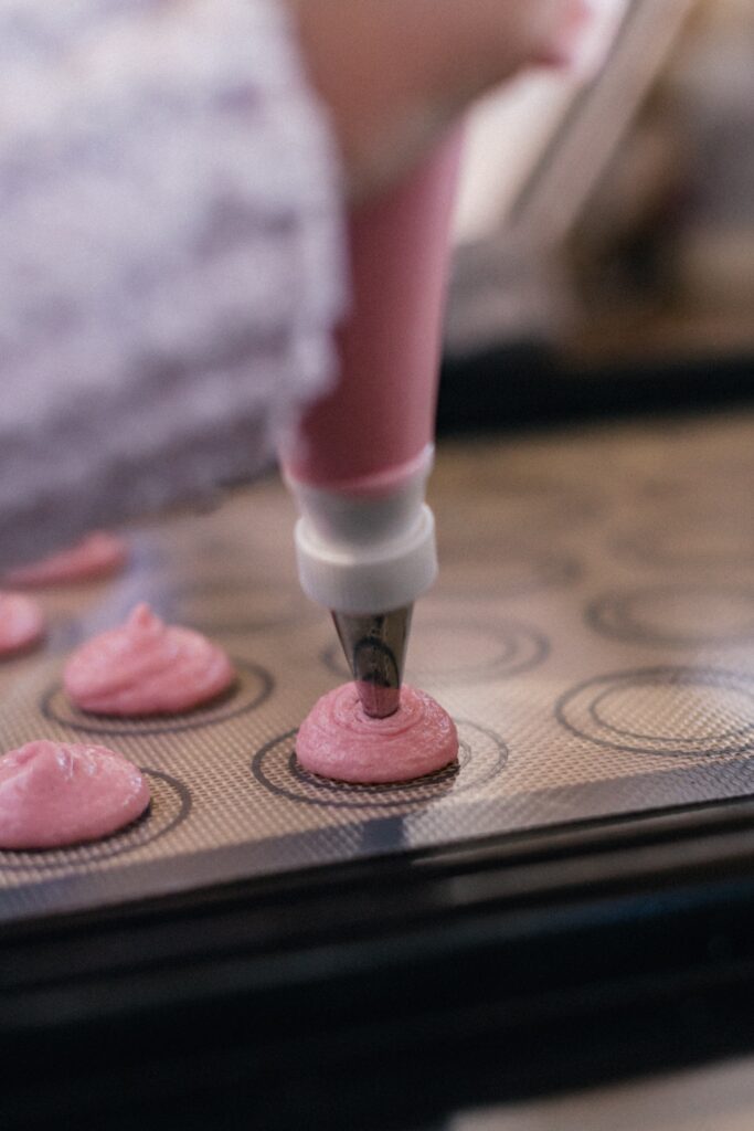 Piping pink batter onto a tray