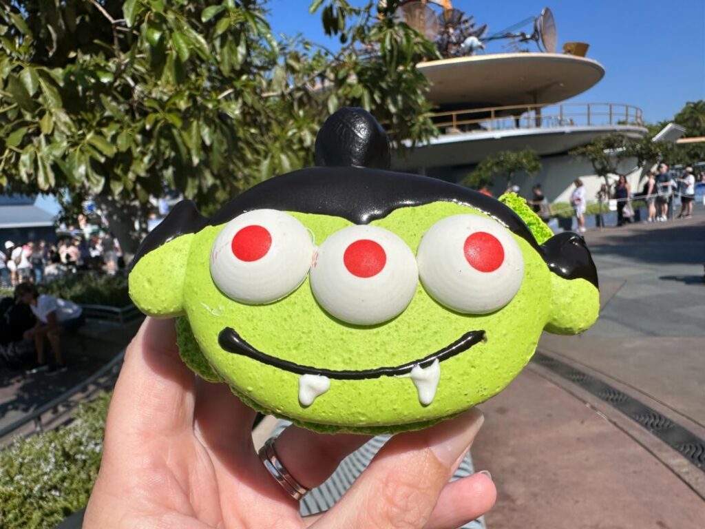 A green macaron decorated like a vampire alien from Toy Story