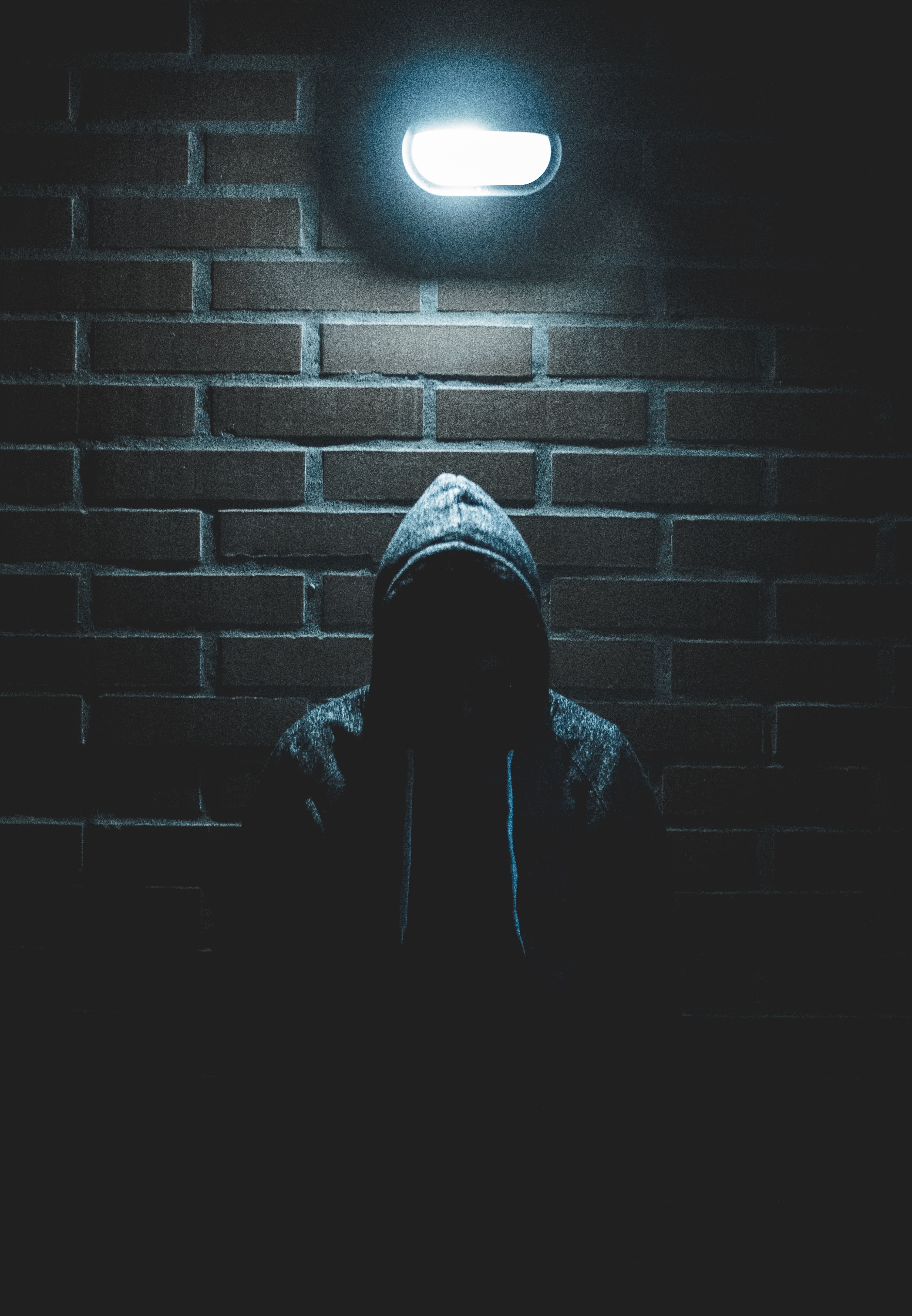 A hooded figure in an alleyway.